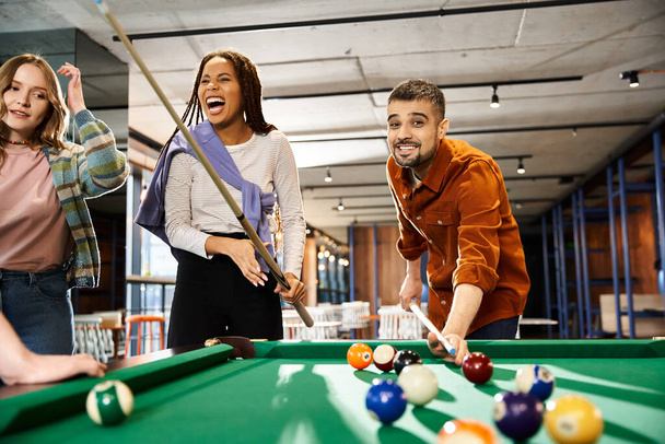 Colleagues in a coworking space enjoying a game of pool, fostering teamwork and camaraderie in a modern business setting. - Photo, Image