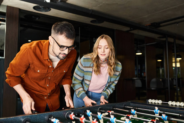 A man and a woman energetically engage in a game, showcasing teamwork and camaraderie in a modern coworking space. - Photo, Image