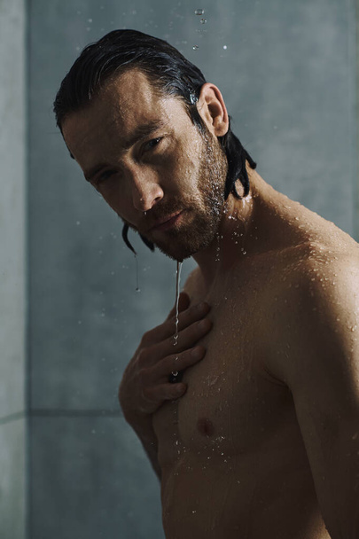 Un bell'uomo pulisce sotto una doccia rinfrescante nella sua routine mattutina. - Foto, immagini