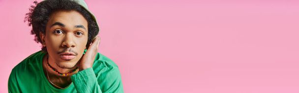 カジュアルな服を着たカーリーな髪を持つ驚くべき若いアフリカ系アメリカ人男性は,ピンクの背景に驚くような表情を示しています. - 写真・画像