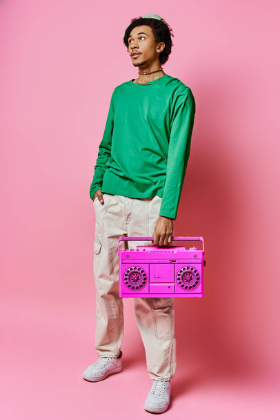 A cheerful young African American man holding a pink boombox in front of a vibrant pink background. - Photo, Image