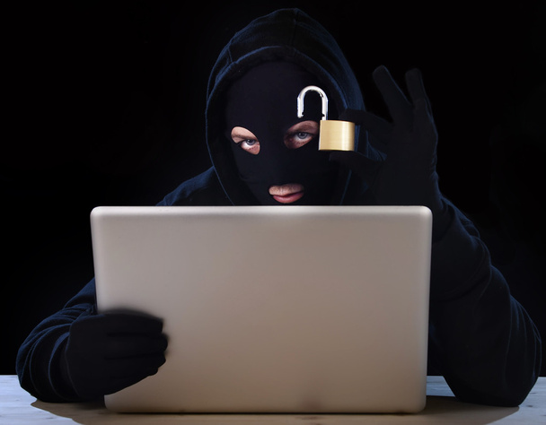 dangerous hacker man with computer and lock hacking system in cyber crime concept - Valokuva, kuva