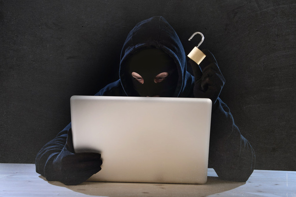 コンピューターとサイバー犯罪概念でシステムをハッキング ロック危険なハッカーの男 - 写真・画像