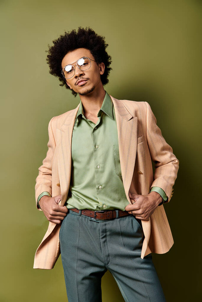 Elegante uomo afroamericano in giacca e cravatta e occhiali da sole posa con fiducia su uno sfondo verde. - Foto, immagini
