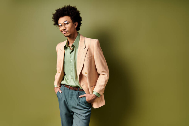 Ein junger Afroamerikaner, stilvoll gekleidet, steht selbstbewusst vor einer leuchtend grünen Wand und trägt eine trendige Sonnenbrille. - Foto, Bild