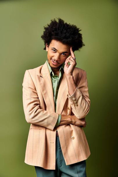 Fiatal afro-amerikai férfi barna öltönyben, zöld ing zöld háttérrel. - Fotó, kép