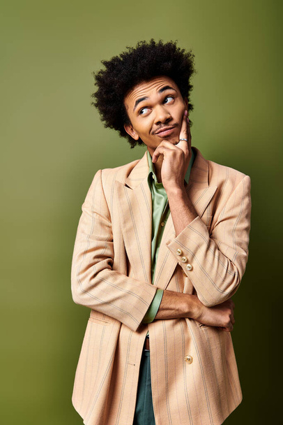 Un giovane uomo afroamericano elegante con i capelli ricci sembra sorpreso su uno sfondo verde vibrante. - Foto, immagini