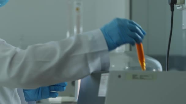 Чоловік у білому пальто та захисні рукавички працює в хімічній лабораторії з науковим інструментом. Повільний рух - Кадри, відео