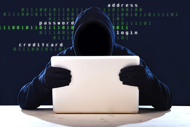 хакер в черном капюшоне и маске с компьютерной системой взлома ноутбука в цифровом злоумышленнике
 - Фото, изображение