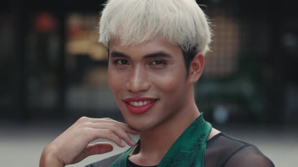 Porträt des extravaganten Transsexuellen, der mit rotem Lippenstift und modernem Haarschnitt draußen posiert. Selbstbewusste Person im Freien, die in die Kamera blickt. Diversity LGBT-Konzept - Filmmaterial, Video