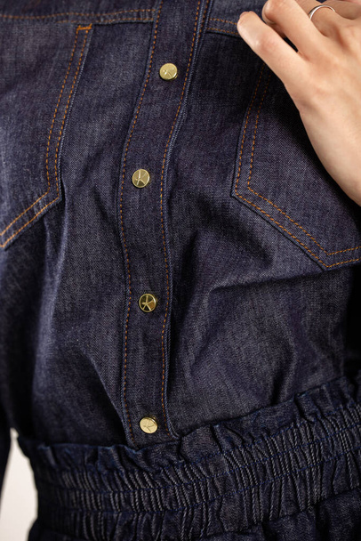 Blue denim shirt with gold buttons. Collar, long sleeves, golden cuff buttons, front fastened with six gold buttons. - Photo, Image