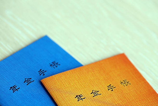 Japon emeklilik sigortası broşürleri masada. Japon emekliler için mavi ve turuncu pansiyon defteri. - Fotoğraf, Görsel