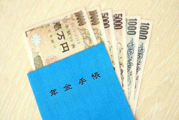 Japán nyugdíjbiztosítási könyv az asztalon jenes pénzzel. Kék könyv a japán nyugdíjasok számára bezár - Fotó, kép