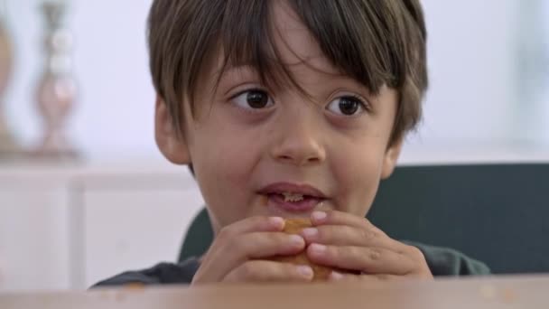 Alegre niño disfrutando de una magdalena durante un sabroso tiempo de trato - Imágenes, Vídeo