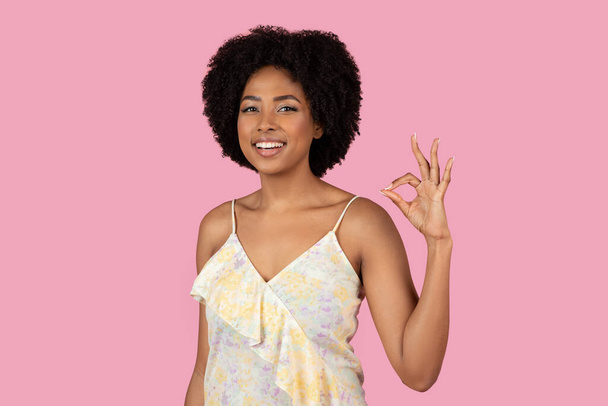 Уверенная афроамериканка дает идеальный знак OK руки, счастливый и улыбаясь на розовом фоне - Фото, изображение