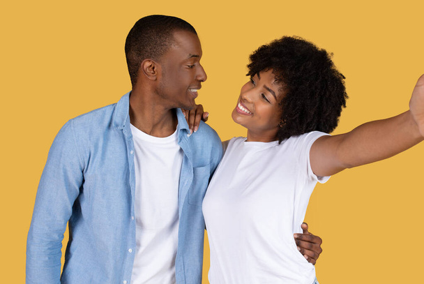 Una giovane coppia afroamericana posa giocosamente mentre si fa un selfie, mostrando un momento di gioia e connessione - Foto, immagini