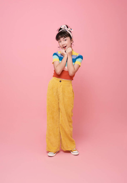 портрет маленькая азиатская девочка улыбается веселый симпатичный взгляд камеры изолированы на розовом фоне. - Фото, изображение