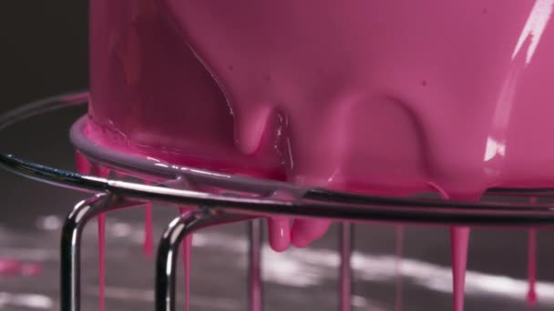 ビスケットケーキの上にピンクの釉薬を注ぐ. デザートの上にピンク色のチョコレートシロップをグラスティング. プロのペストリーシェフによるペストリーの装飾を閉じます. 新鮮な調理されたスーパーおいしいケーキ - 映像、動画