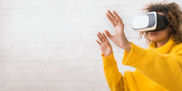 Tulevaisuus on nyt. Nainen käyttää VR-kuulokkeita ja elehtii, viettää aikaa kotona, vapaa tila - Valokuva, kuva