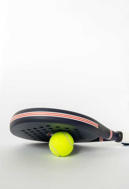 blauw professioneel paddle tennisracket met gele bal op witte achtergrond. kopieer ruimte voor tekst - Foto, afbeelding