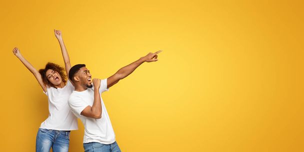 Αφρο-αμερικάνικο ζευγάρι τρελαίνεται, χορεύει και τραγουδάει σε πορτοκαλί φόντο στούντιο - Φωτογραφία, εικόνα
