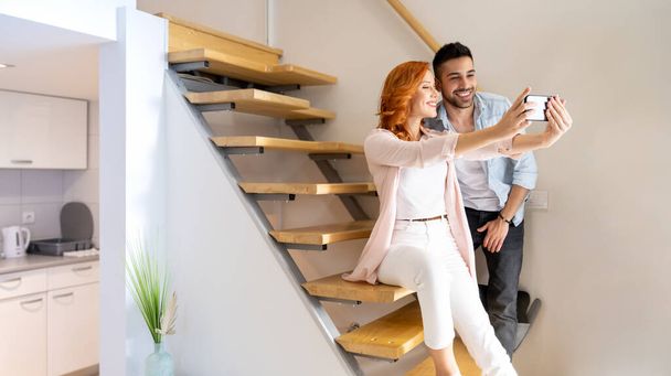 Schattig, jong en gelukkig paar nemen van een selfie samen op de trap thuis - Foto, afbeelding