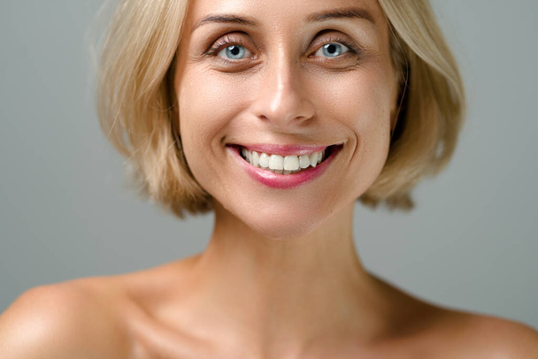 Natural beauty. Blonde woman with healthy skin.  No makeup. Grey background. - Фото, изображение