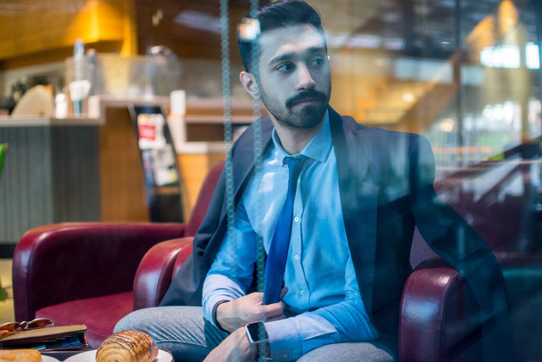 Pensive pohledný podnikatel drží kravatu a dívá se oknem - Fotografie, Obrázek