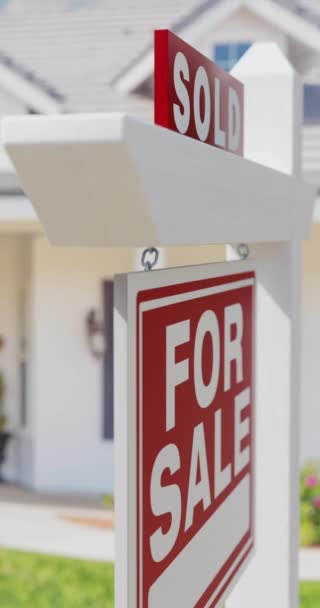 Pan verticale di un venduto in vendita Immobiliare segno con una nuova casa sullo sfondo. - Filmati, video
