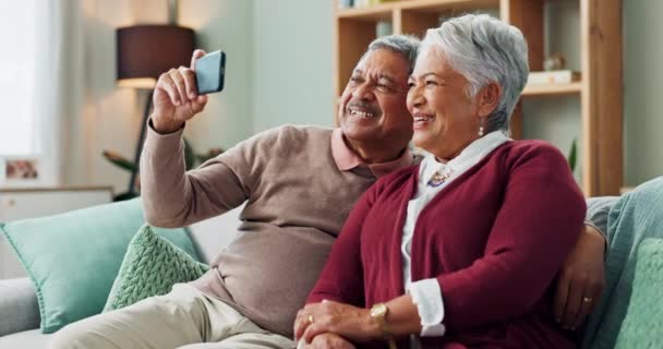 Senior couple, happy and smartphone for video call, contact and communication in living room. People, mature man and woman on sofa, couch and house together with cellphone for online conversation. - Footage, Video