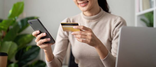 オンライン決済, 女性手 クレジットカードを保持し,自宅でオンラインショッピングのためにスマートフォンを使用. - 写真・画像