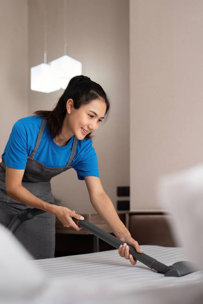 Pracovník úklidové služby odstraňuje nečistoty s profesionálním vybavením. Žena hospodyně čištění matrace na posteli s vysavačem. - Fotografie, Obrázek