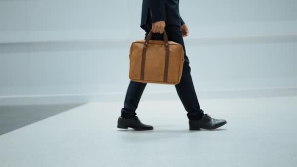 バッグを持っている間歩いているプロのビジネスマンの足の閉鎖. 脚に焦点を当てたプロジェクトマネージャーのクロップされたイメージ. 旅行,移動,旅,歩く,新しいポジションを得る,転職する. エクササイズ. - 映像、動画