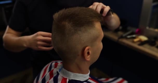 Peluquería corta el cabello del cliente masculino en el salón de belleza. Peluquería profesional en una peluquería - Imágenes, Vídeo