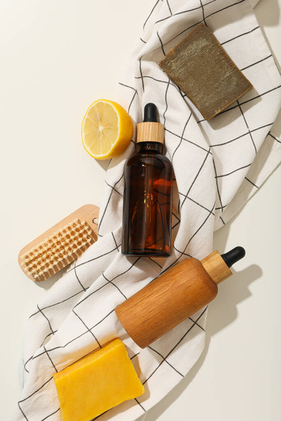 Бутылки для сыворотки, лимона, щетки и полотенца на светлом фоне, вид сверху - Фото, изображение