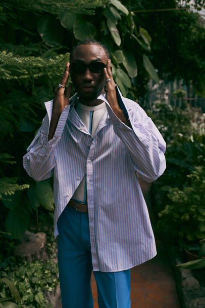Un hombre afroamericano apuesto en un jardín verde vibrante. - Foto, imagen