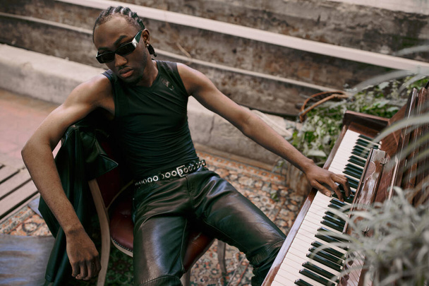 Афроамериканський чоловік сидить на лавці біля піаніно в яскравому зеленому саду. - Фото, зображення