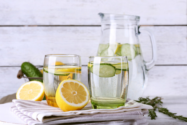 Свіжа вода з лимоном та огірком у скляному посуді на дерев'яному фоні
 - Фото, зображення