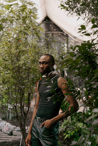 Un homme afro-américain sophistiqué se trouve au cœur d'une forêt luxuriante. - Photo, image