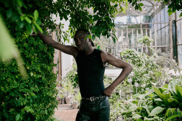 Красивий афроамериканський чоловік з витонченим стилем, що стоїть поруч з пишним зеленим лісом. - Фото, зображення