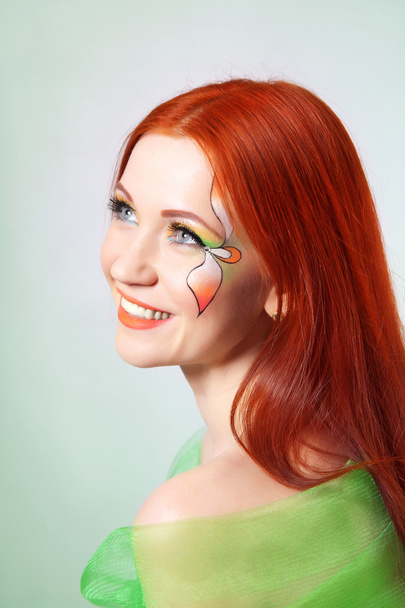 Retrato de una hermosa chica pelirroja con una flor pintada en su cara
 - Foto, Imagen