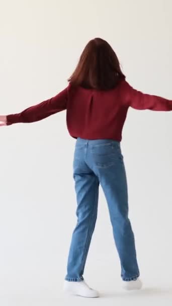 Joyful Caucasian teenage girl dancing happily and laughing over white background. Enjoying festive party mood and relaxing. Vertical video. - Footage, Video