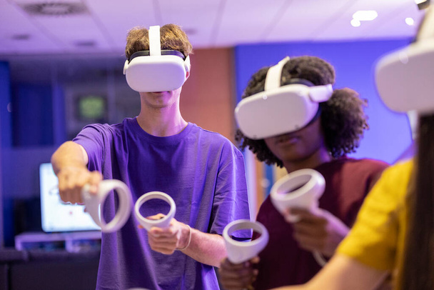 Teenageři nosící VR sluchátka jsou uchváceni ponořujícím herním zážitkem ve virtuálním prostředí. - Fotografie, Obrázek