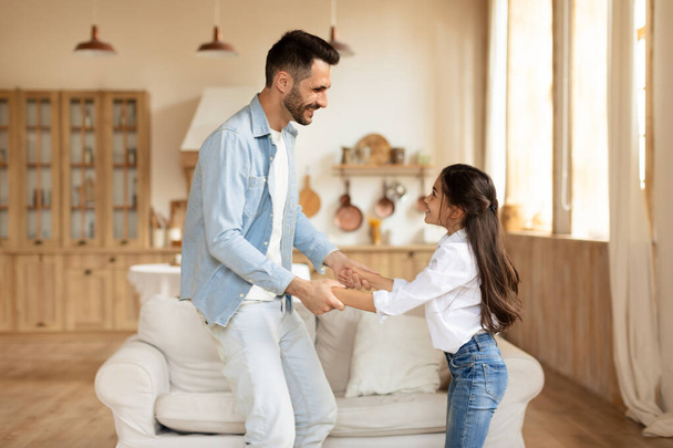Um momento delicioso de uma jovem desfocada dançando com seu pai em uma sala de estar brilhante em casa - Foto, Imagem