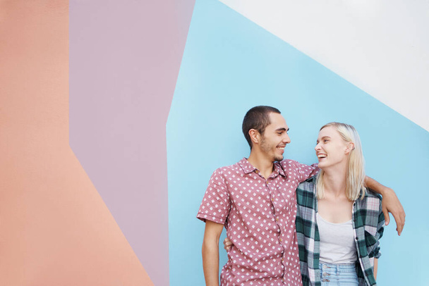Paar, jung und alt, glücklich im Atelier und umarmt sich zum gemeinsamen Lachen und zur lässigen Mode auf Farbblock-Hintergrund. Mockup-Raum, bunte Wand und stilbewusste Menschen. - Foto, Bild