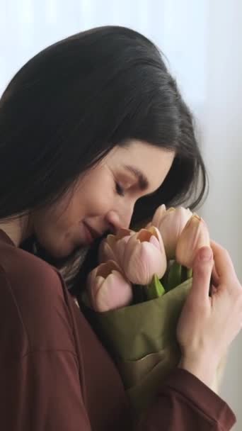 Detailní portrét pozitivní a šťastný běloška těší kytice, vůně tulipánů. Radostný dar. Svislé video. - Záběry, video