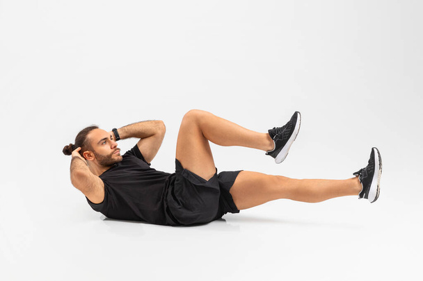 Mies keskittynyt suorittamaan vatsan liikuntaa eristetty valkoisella taustalla, urheilullinen elämäntapa käsite - Valokuva, kuva
