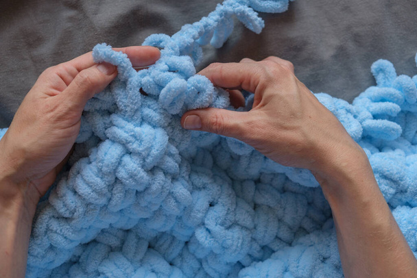 Uma mulher carinhosamente elabora um cobertor azul para seu neto com suas próprias mãos, cada um costurar um testamento para seu cuidado e devoção. Criar memórias estimadas com tesouros artesanais. - Foto, Imagem