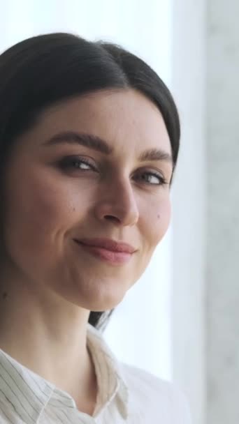 Közelkép egy boldog kaukázusi nőről, mosolyog és a kamerába néz. Női nőiesség és egyéniség koncepció. Függőleges videó. - Felvétel, videó