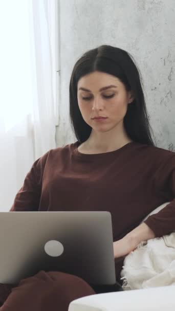 Serieuze en gefocuste vrouwelijke Kaukasische freelancer werkt online met laptop thuis. Op afstand werken of online studeren concept. Verticale video. - Video